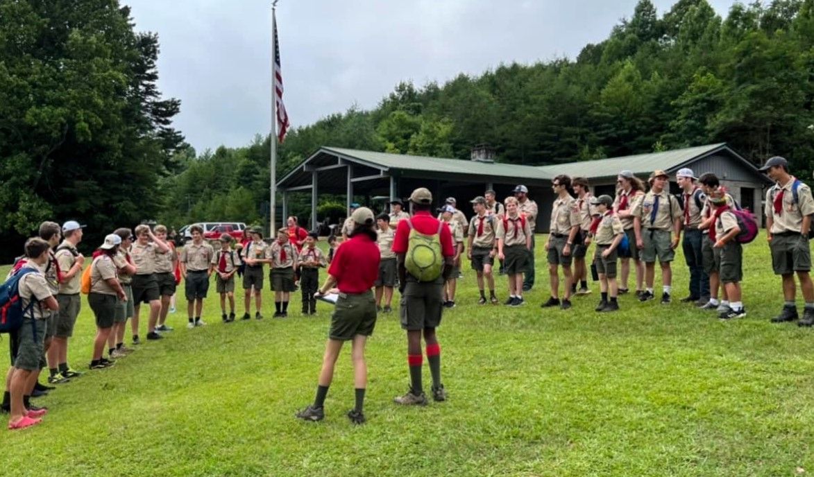 A group of boy scouts are standing in a field.