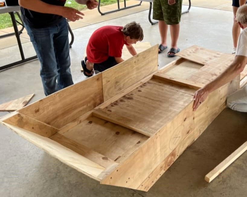 A group of people are working on a wooden boat
