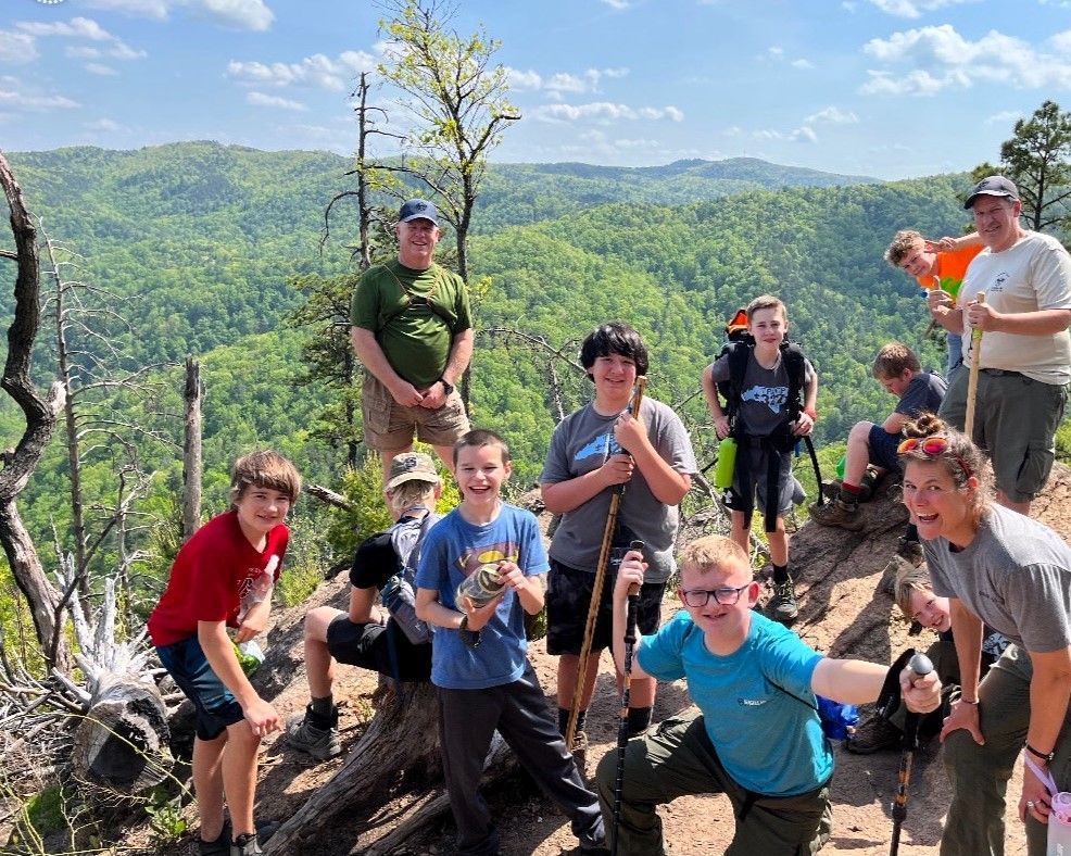 A group of young people are posing for a picture on top of a mountain.