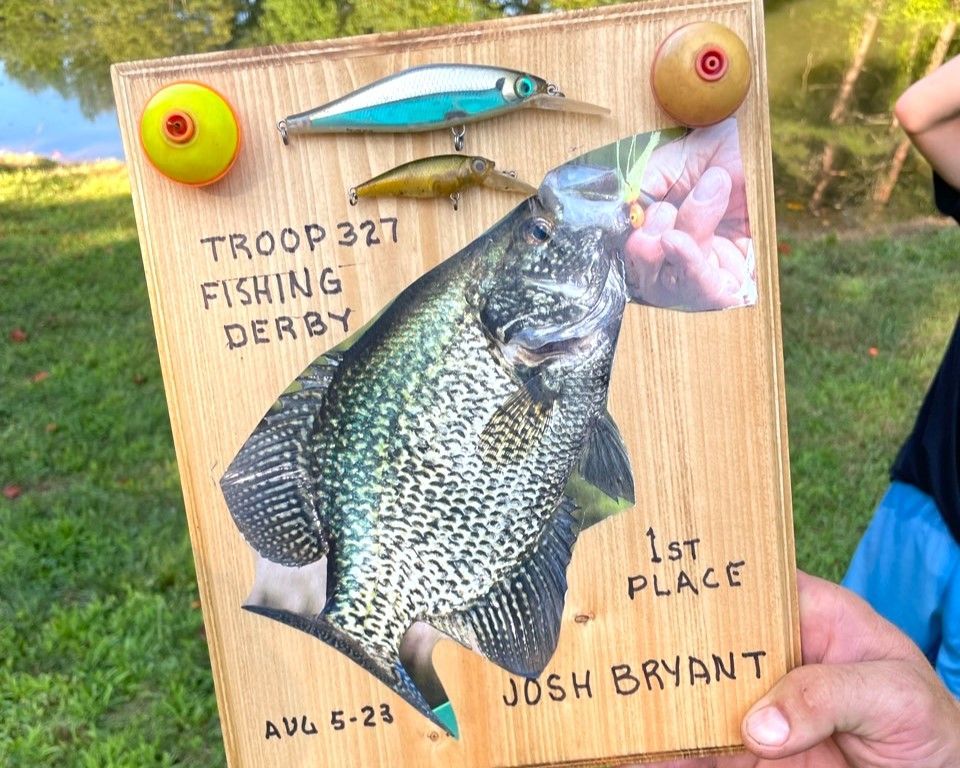 A person is holding a wooden sign with a picture of a fish on it.