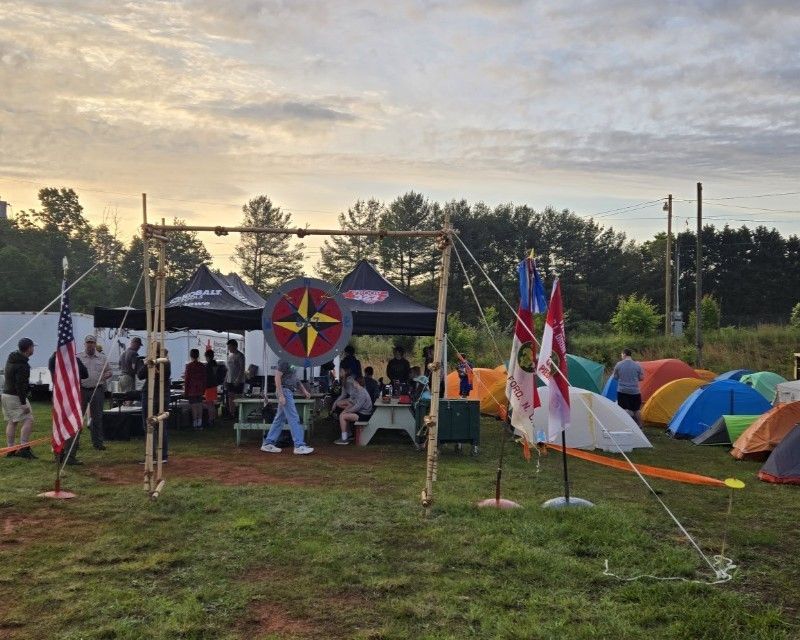A group of people are gathered in a field with tents and flags.