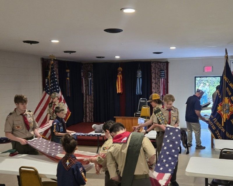 A group of boy scouts are holding flags in a room