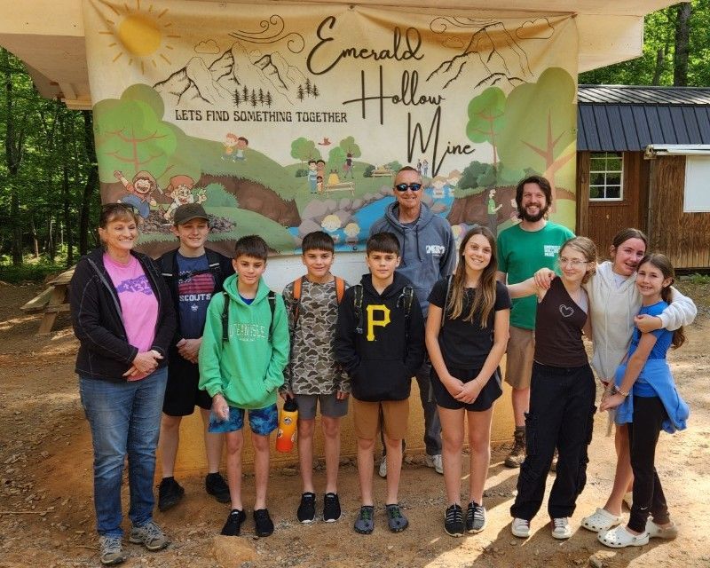 A group of people standing in front of a sign that says emerald hallway mine