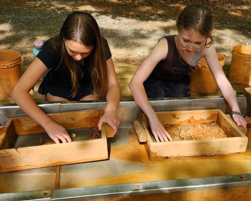 Two young girls are playing with wooden boxes on a table