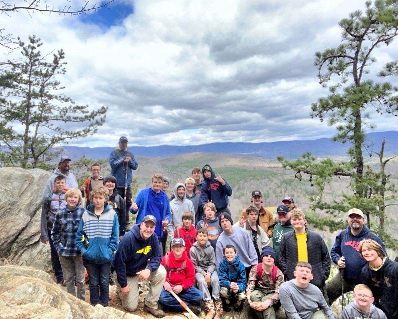 A group of people are posing for a picture on top of a mountain.
