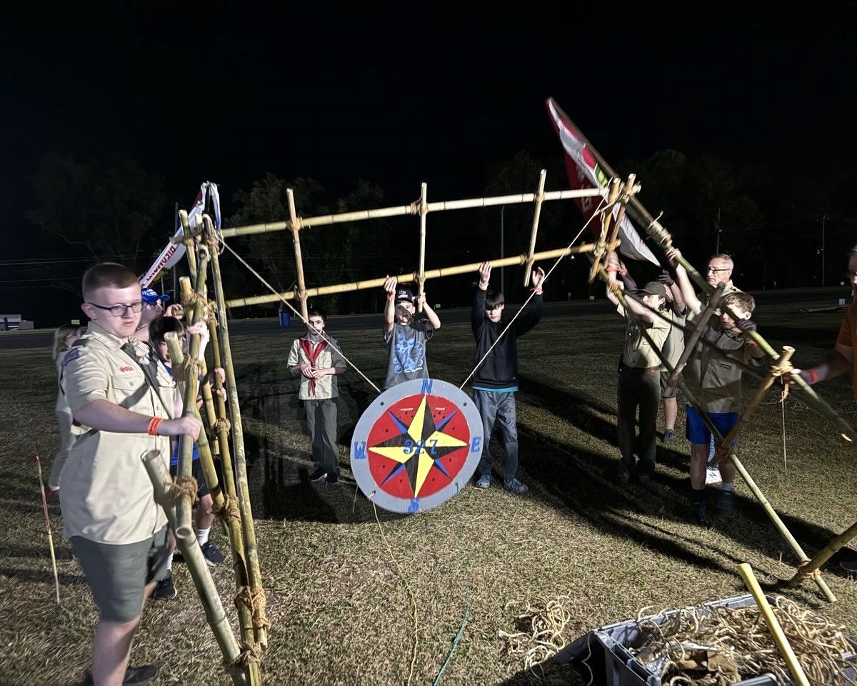 A group of boy scouts are standing around a wooden structure.