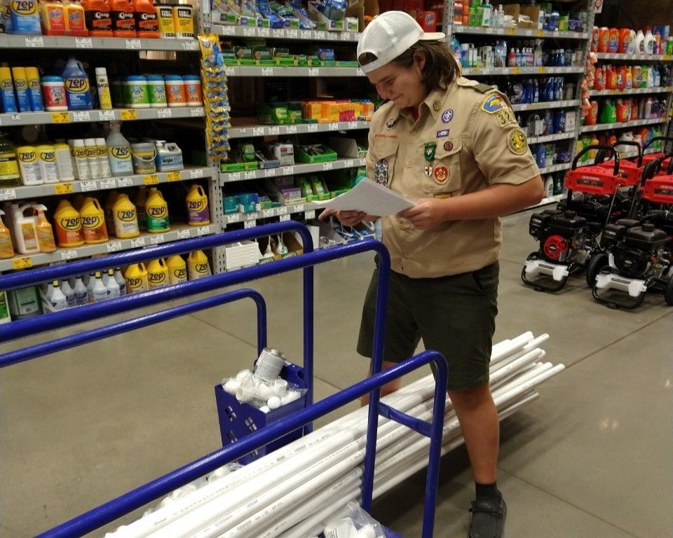 A boy scout is looking at a piece of paper in a store