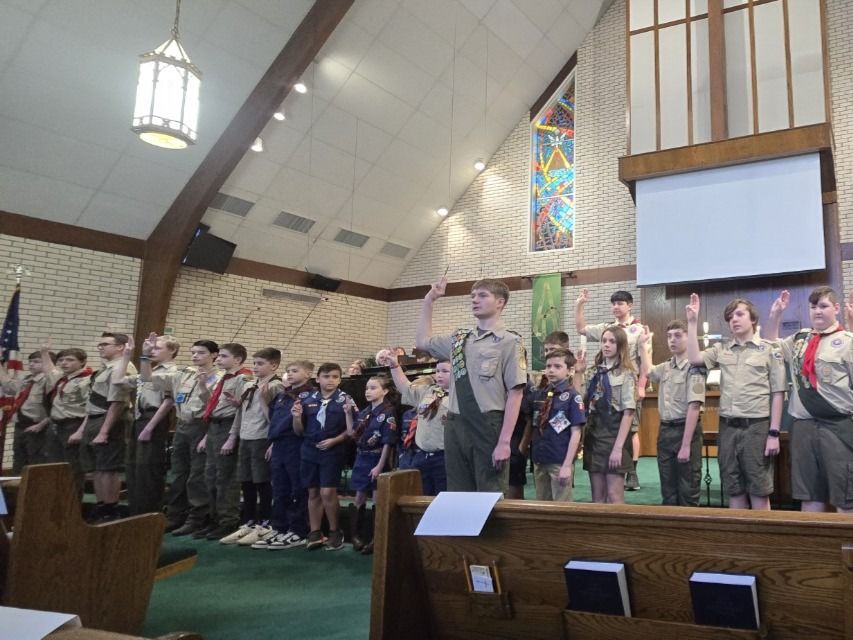 the scouts stand in the front of the church stand, facing the audience