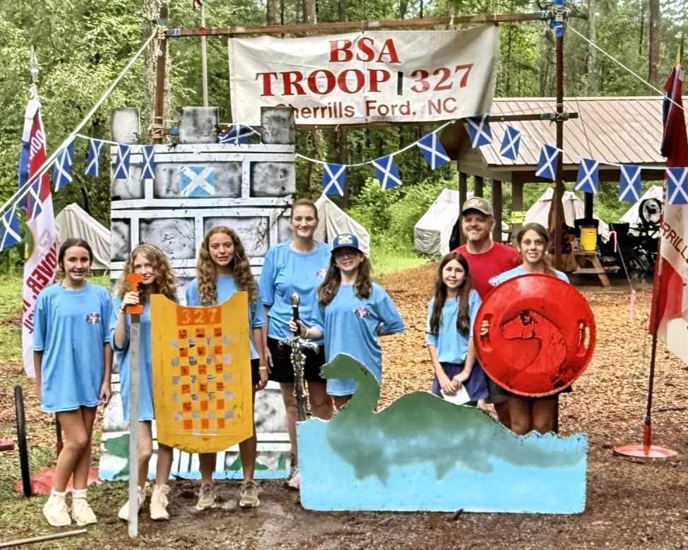 A group of people standing in front of a sign that says bsa troop 327