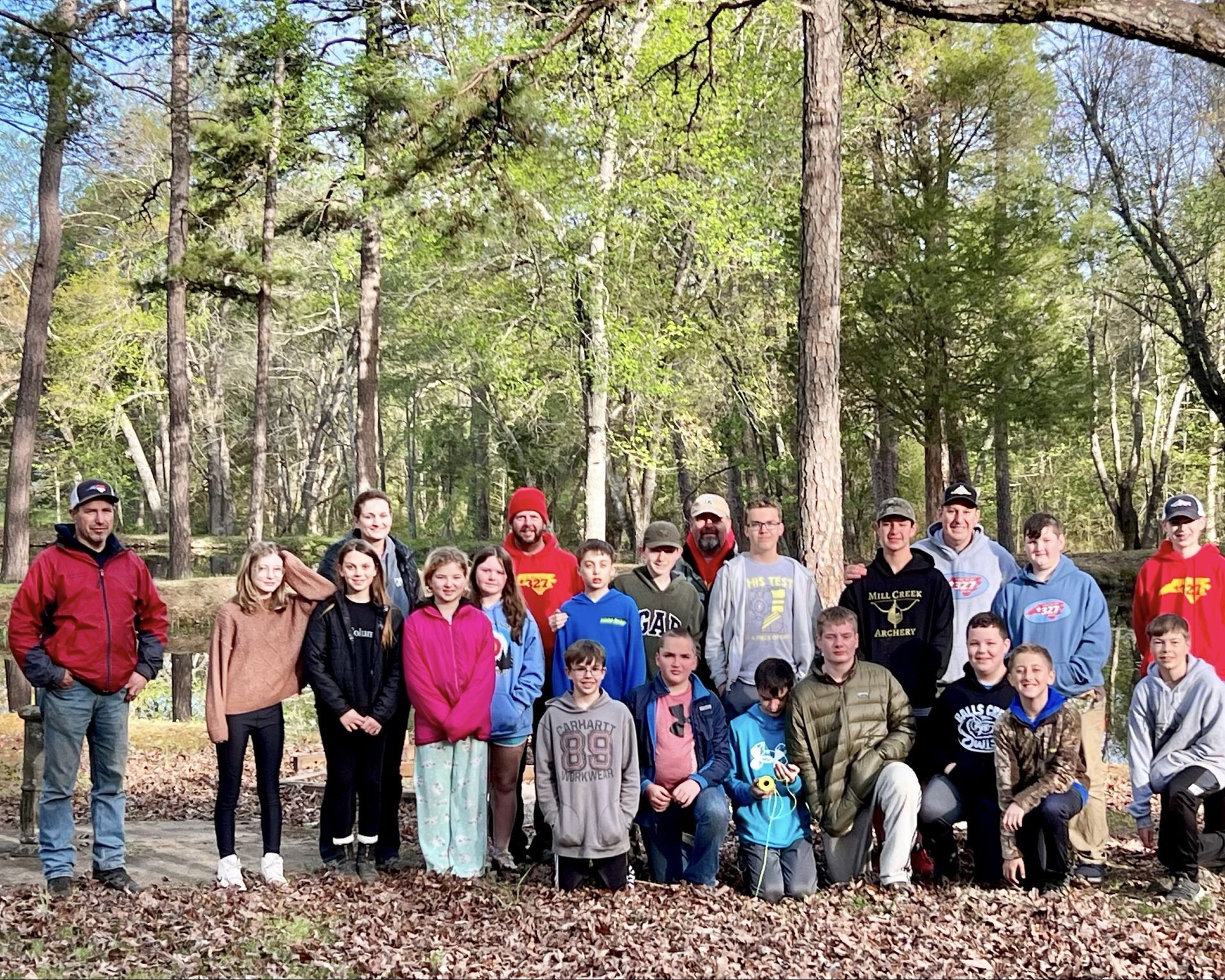 A group of people are posing for a picture in the woods.