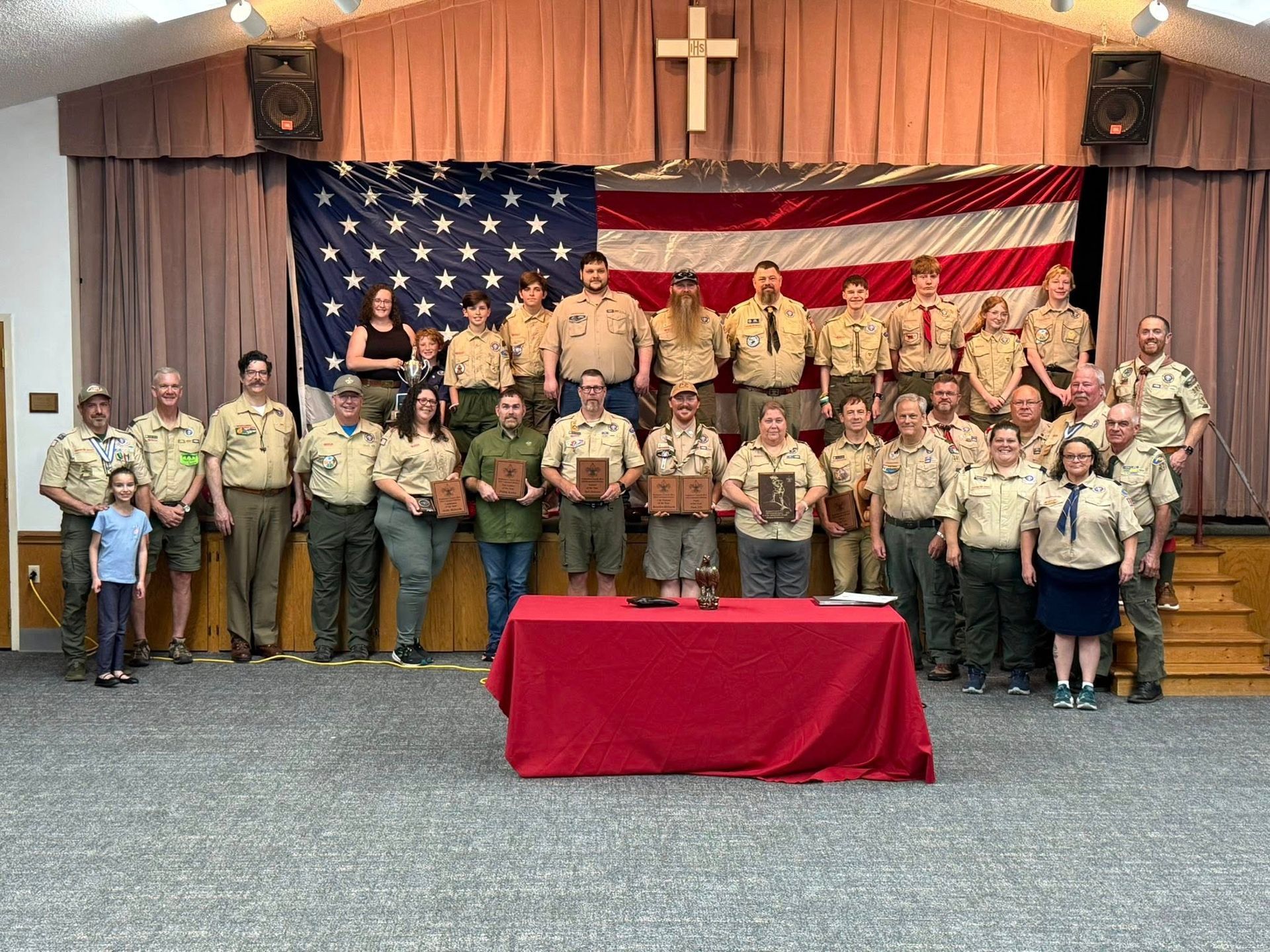 A group of boy scouts are posing for a picture in front of an american flag.