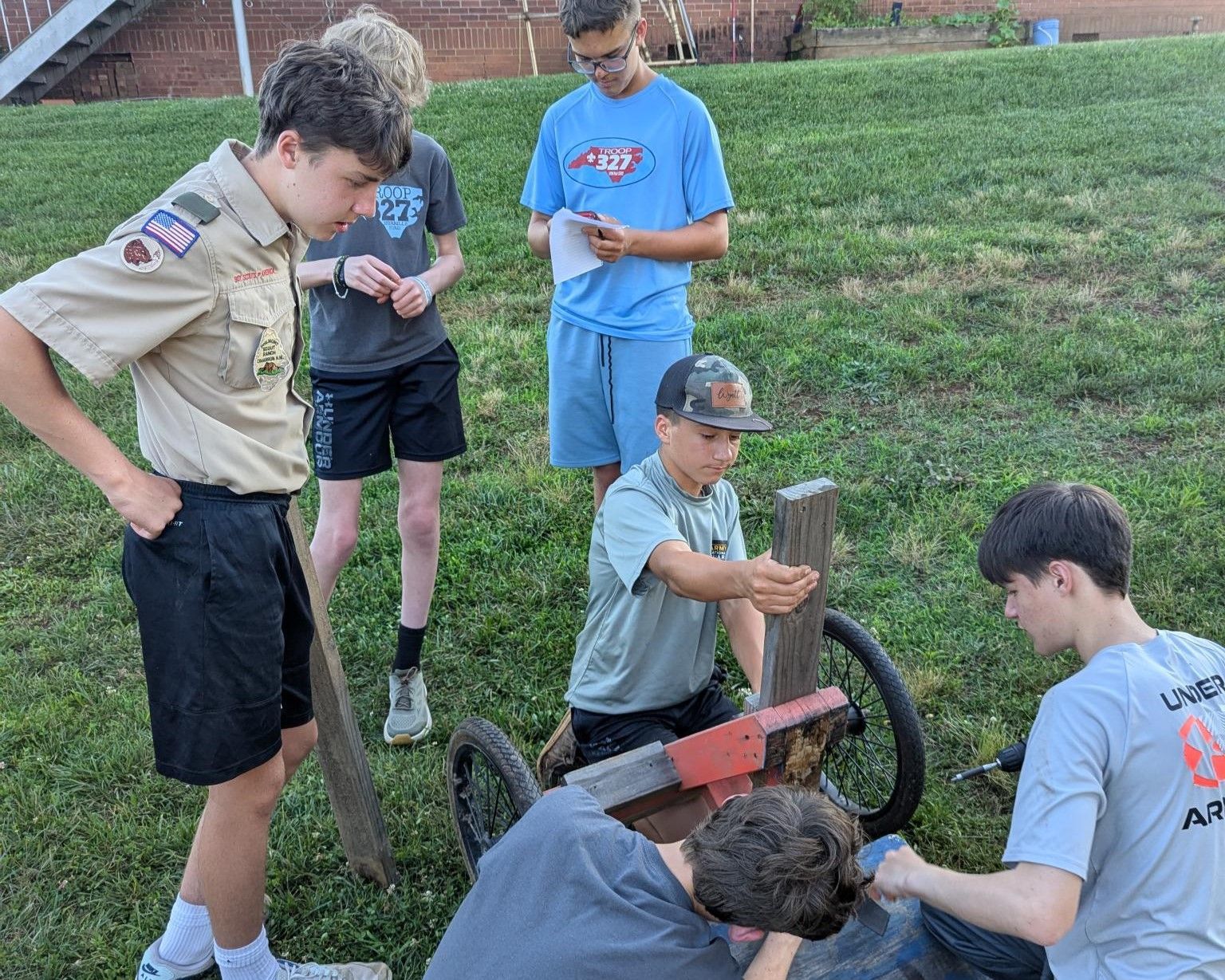 A group of young men are working on a wooden cart.