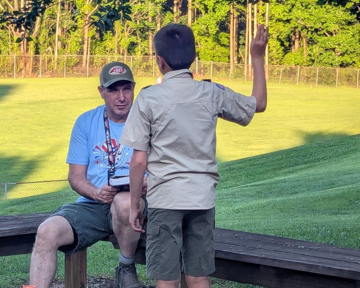 A man is sitting on a bench talking to a boy scout
