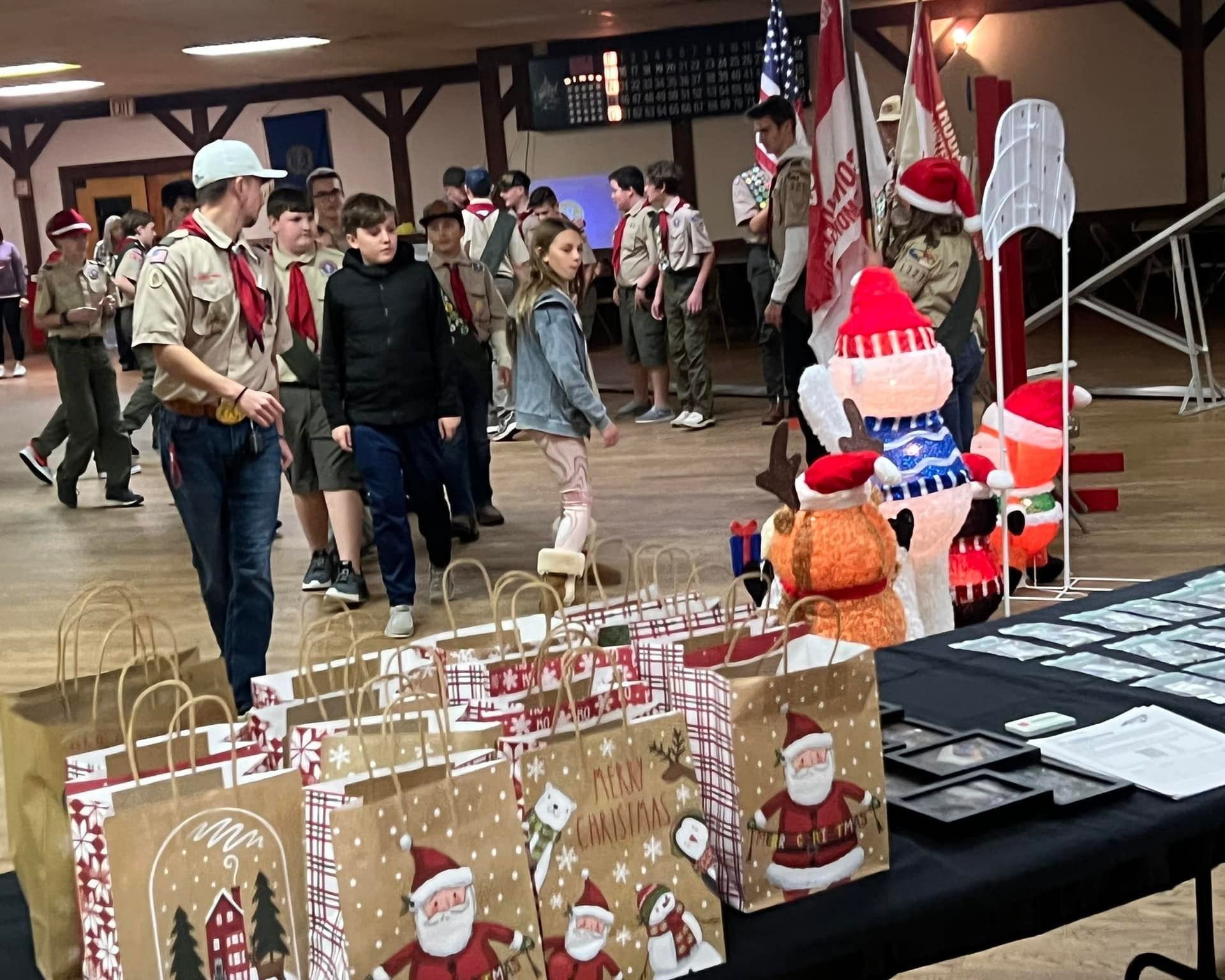 A group of boy scouts are standing around a table with christmas bags.