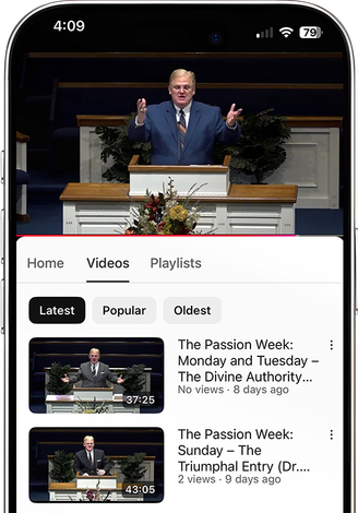 A man is standing at a podium giving a speech on a cell phone.