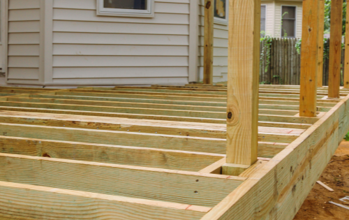 A photo of a deck in the process of being built. The deck has been framed and needs the floorboards and railing installed. Then, it needs a fresh coat of paint.