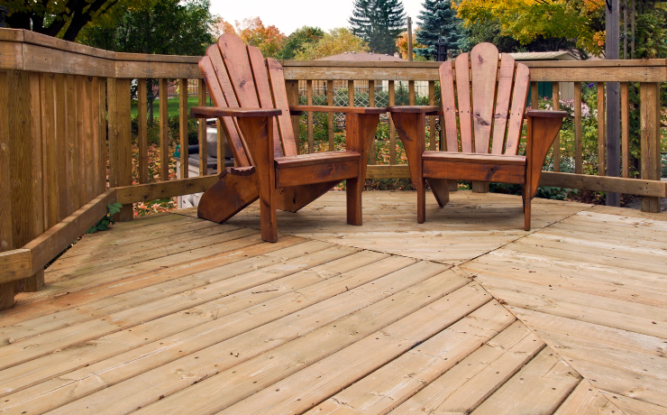 A photo of a small deck built by Hub City Deck Pros. The deck was custom-built to match the shape and contour of the yard. The deck has some lawn chairs as well for people to sit on.