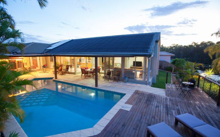 A photo of a stunning pool deck installed next to an inground pool. The deck is on the right side of the pool and overlooks a small hill further on to the right.