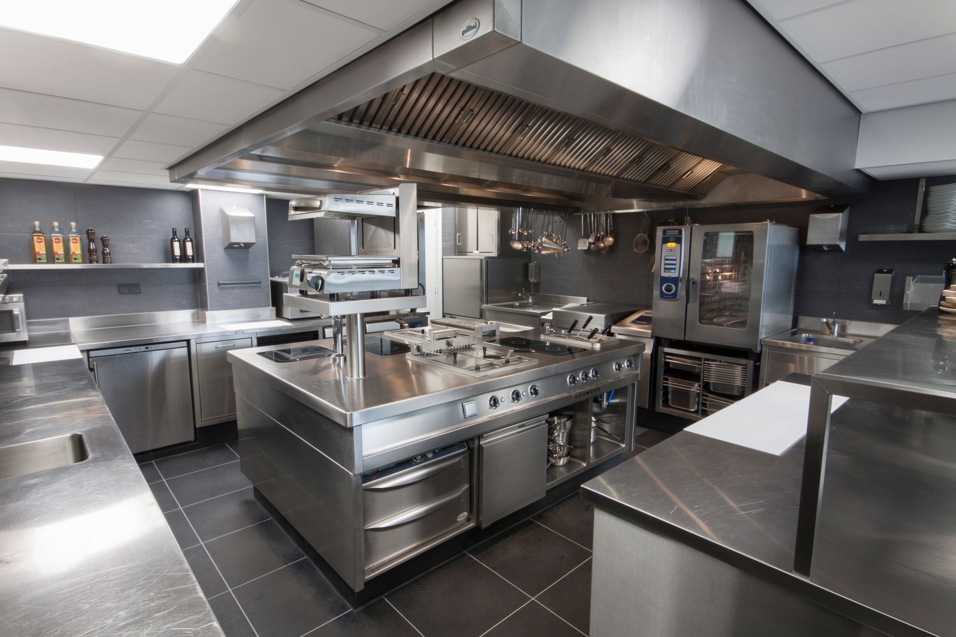 Commercial kitchen with stainless steel appliances and a large hood.
