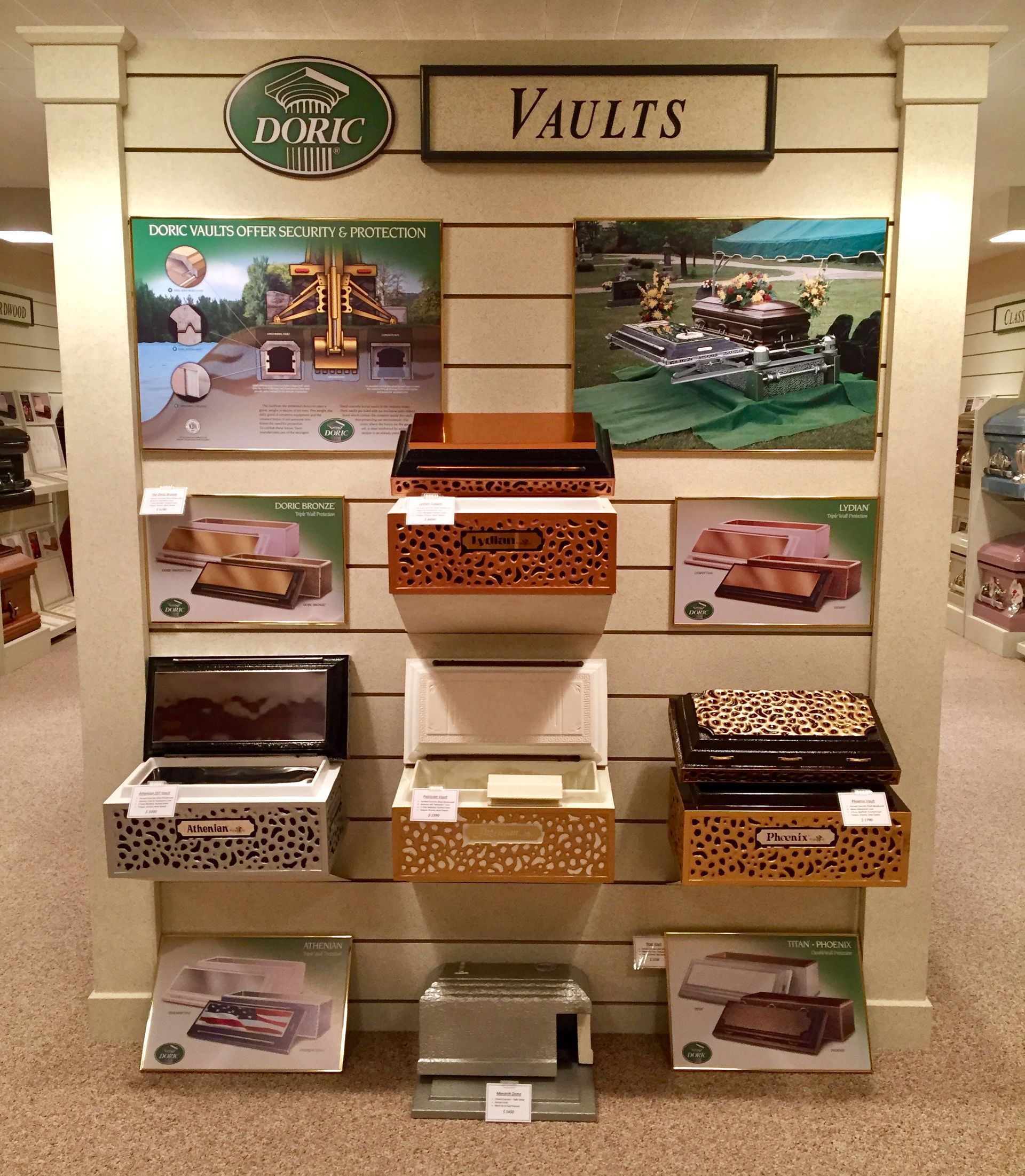 A retail display of burial vaults featuring several models on shelves, with informational signs and brochures.