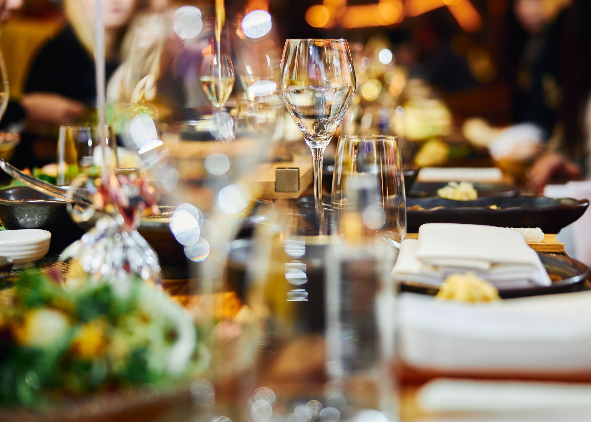 A group of people are sitting at a table with plates of food and wine glasses.