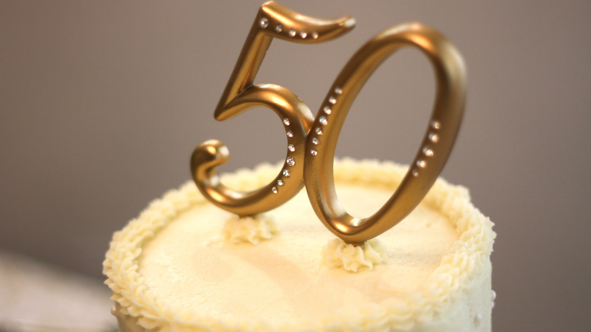 A 50th anniversary cake with a gold candle on top.