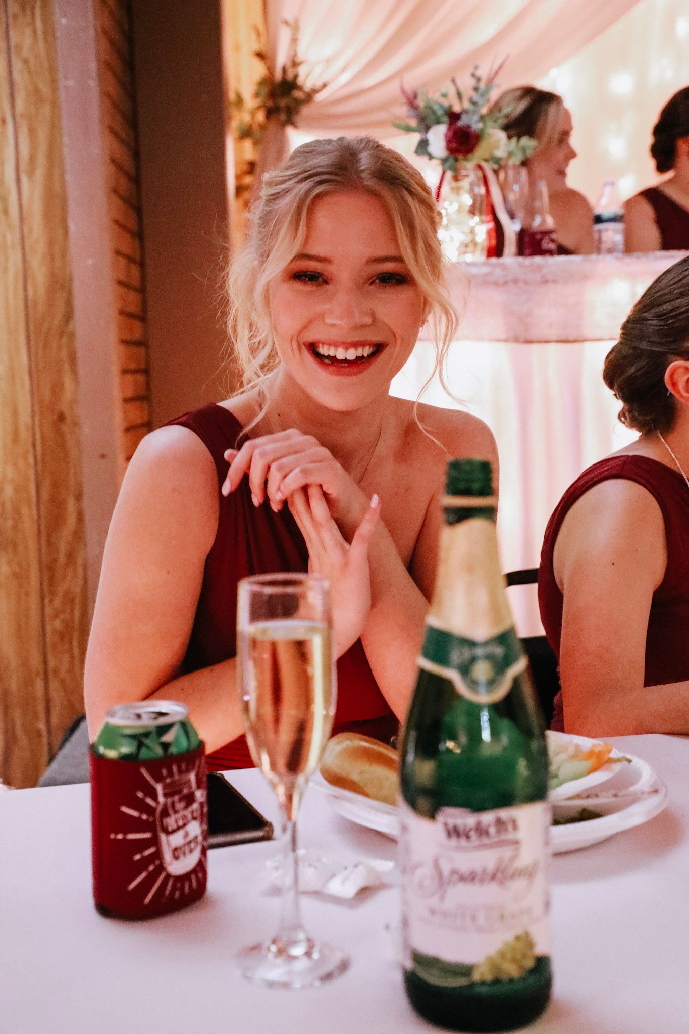 A woman is sitting at a table with a bottle of wine and a glass of champagne.