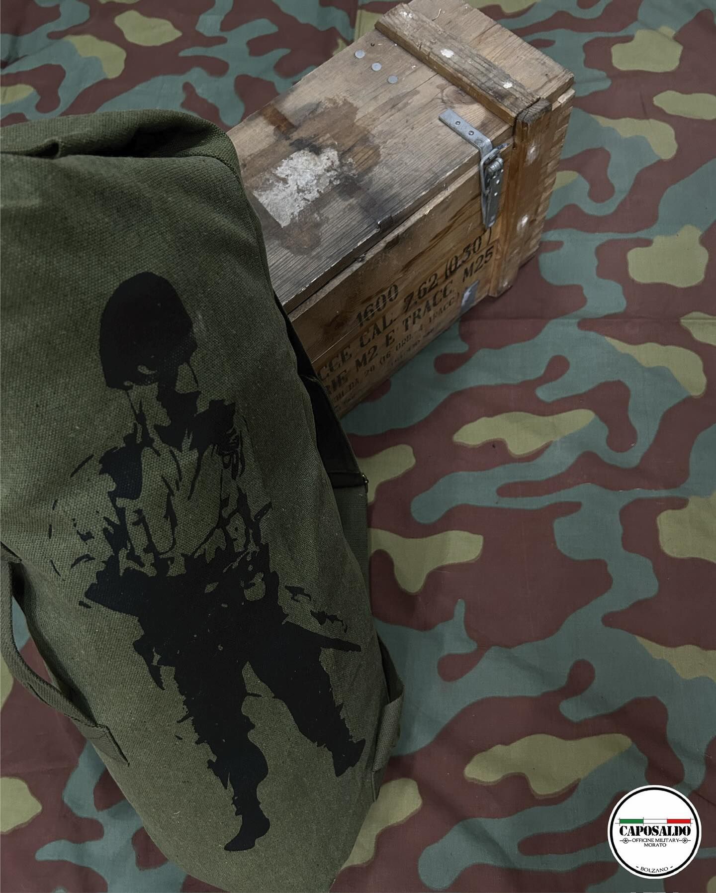 Tessuto mimetico accanto a una scatola di cartone usurata, su una superficie con motivo mimetico.