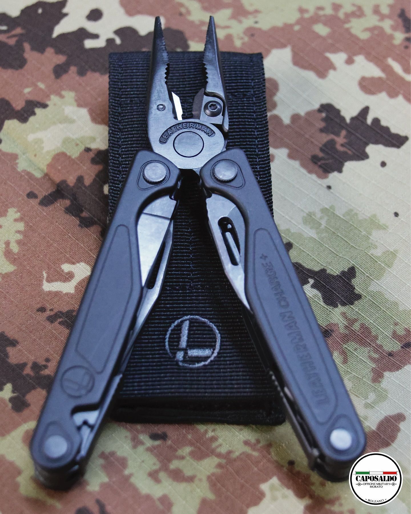 Pinze multiuso nere aperte su una superficie mimetica.