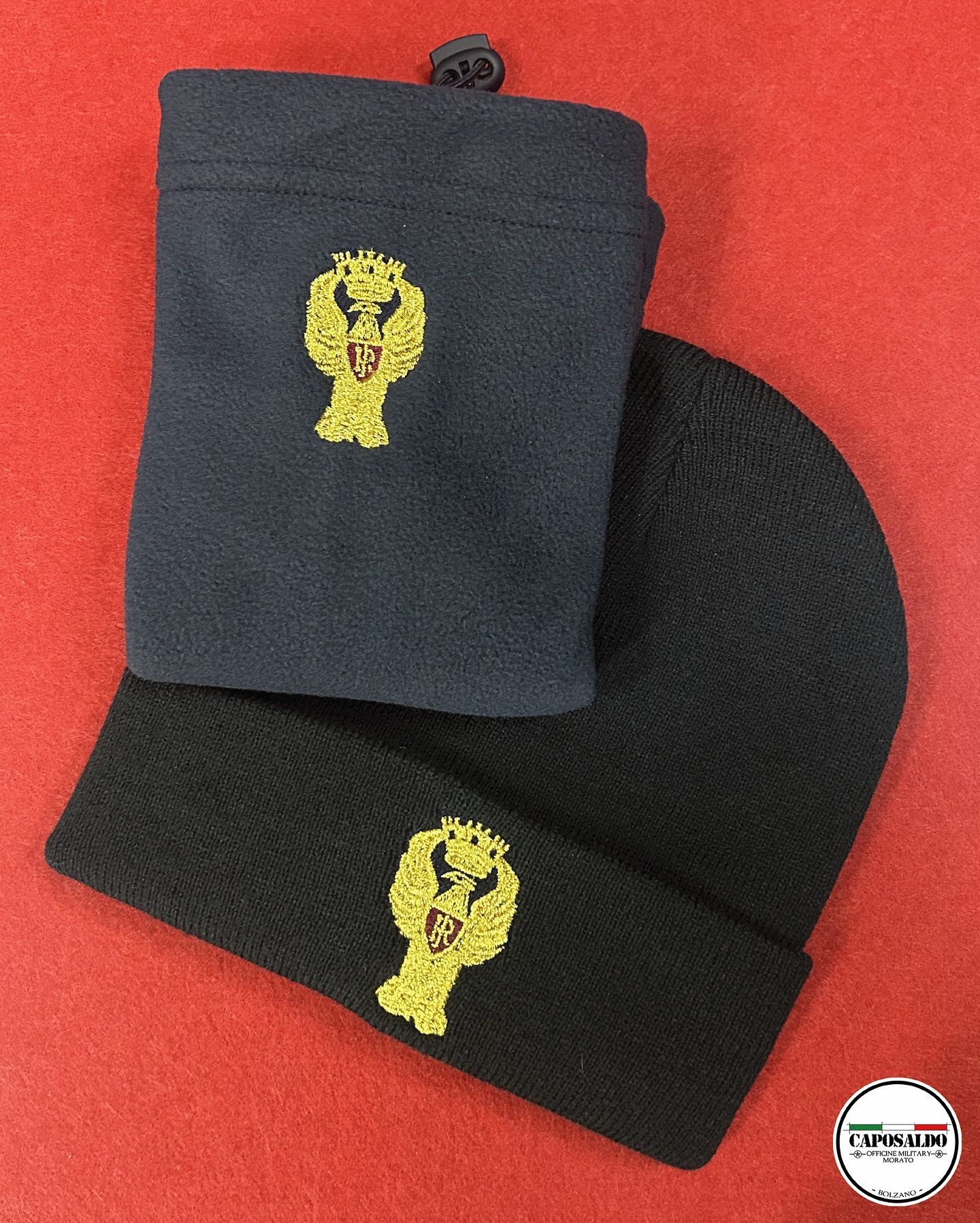 Due berretti neri in maglia con emblemi ricamati in giallo su sfondo rosso