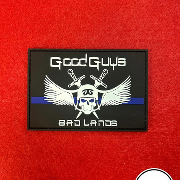 Toppa nera dei Good Guys Bad Lands con teschio, spade incrociate, ali e striscia blu su sfondo di tessuto rosso