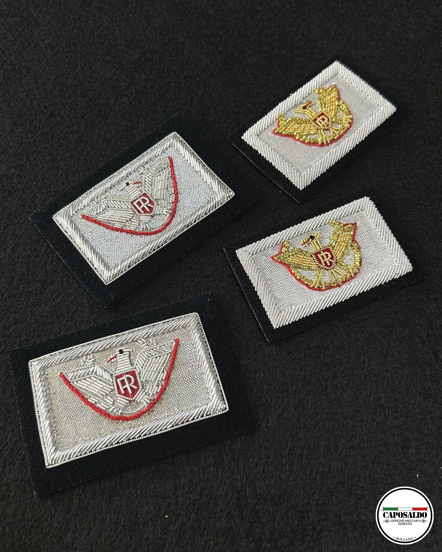 Tre toppe in tessuto ricamate con disegni rossi e dorati su sfondo scuro.