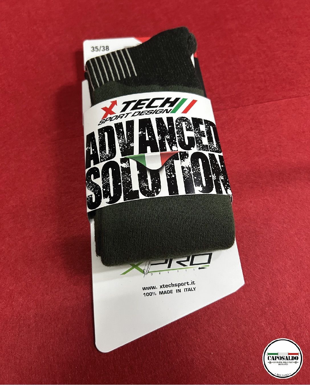 Fascia da polso nera X-TECH Advanced Solution su cartoncino bianco con sfondo rosso.