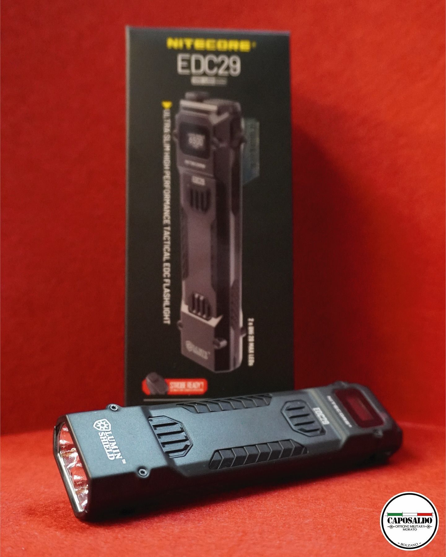 Torcia a LED nera su una superficie rossa accanto alla sua scatola, esposta in un punto vendita.