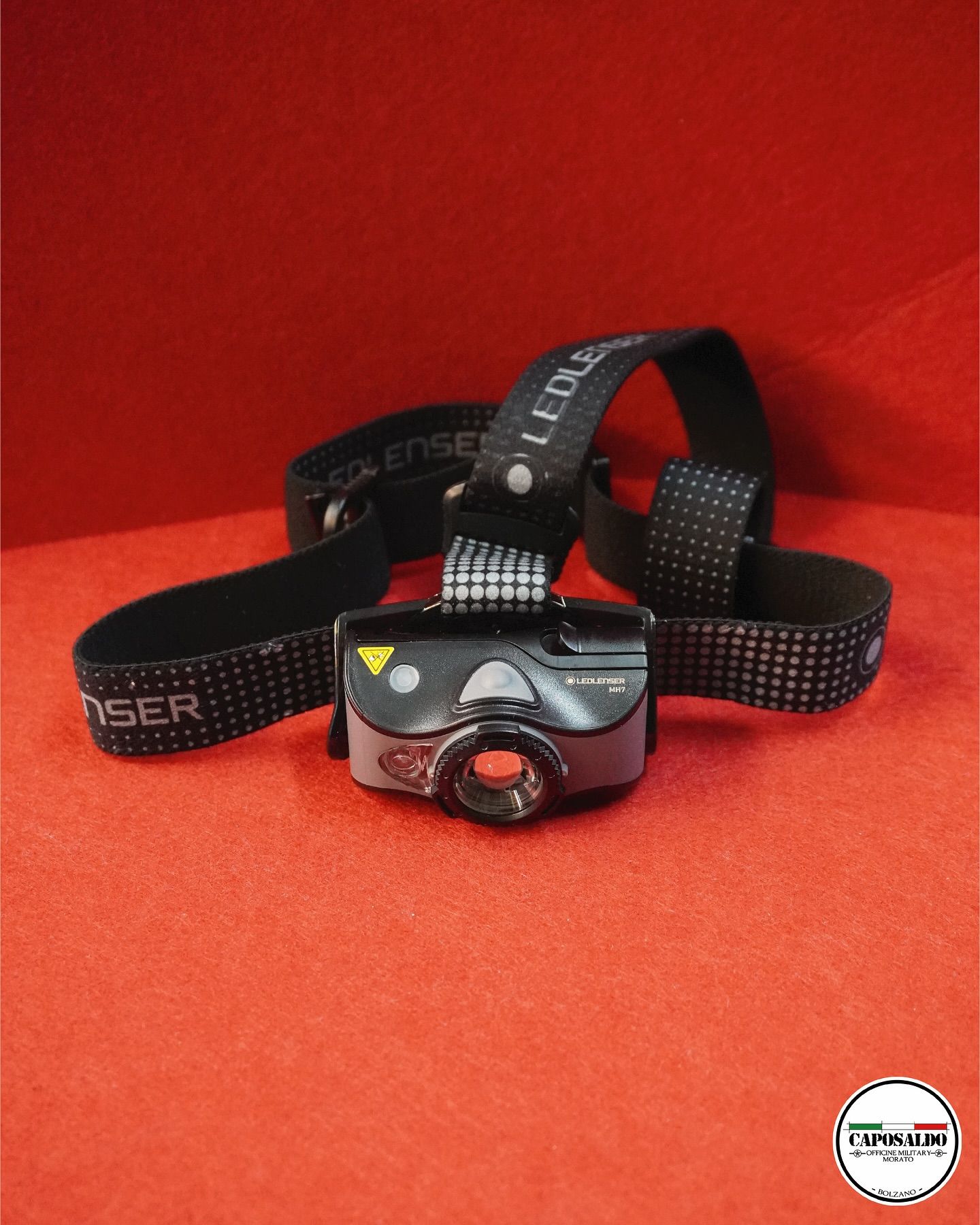 Faro nero su superficie rossa con cinghie elastiche e luce anteriore rossa.