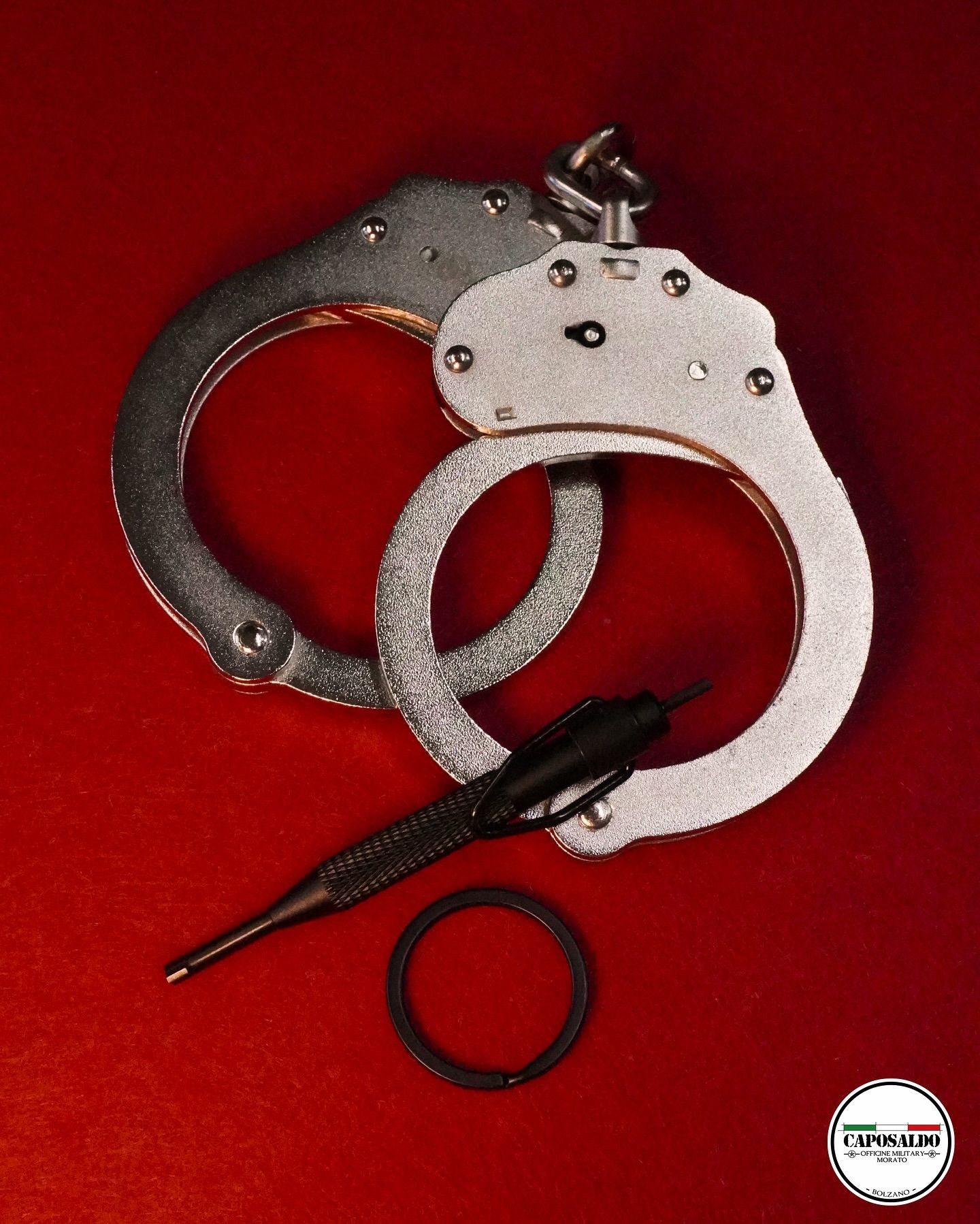 Manette e una penna nera su sfondo rosso, con un anello allentato sotto