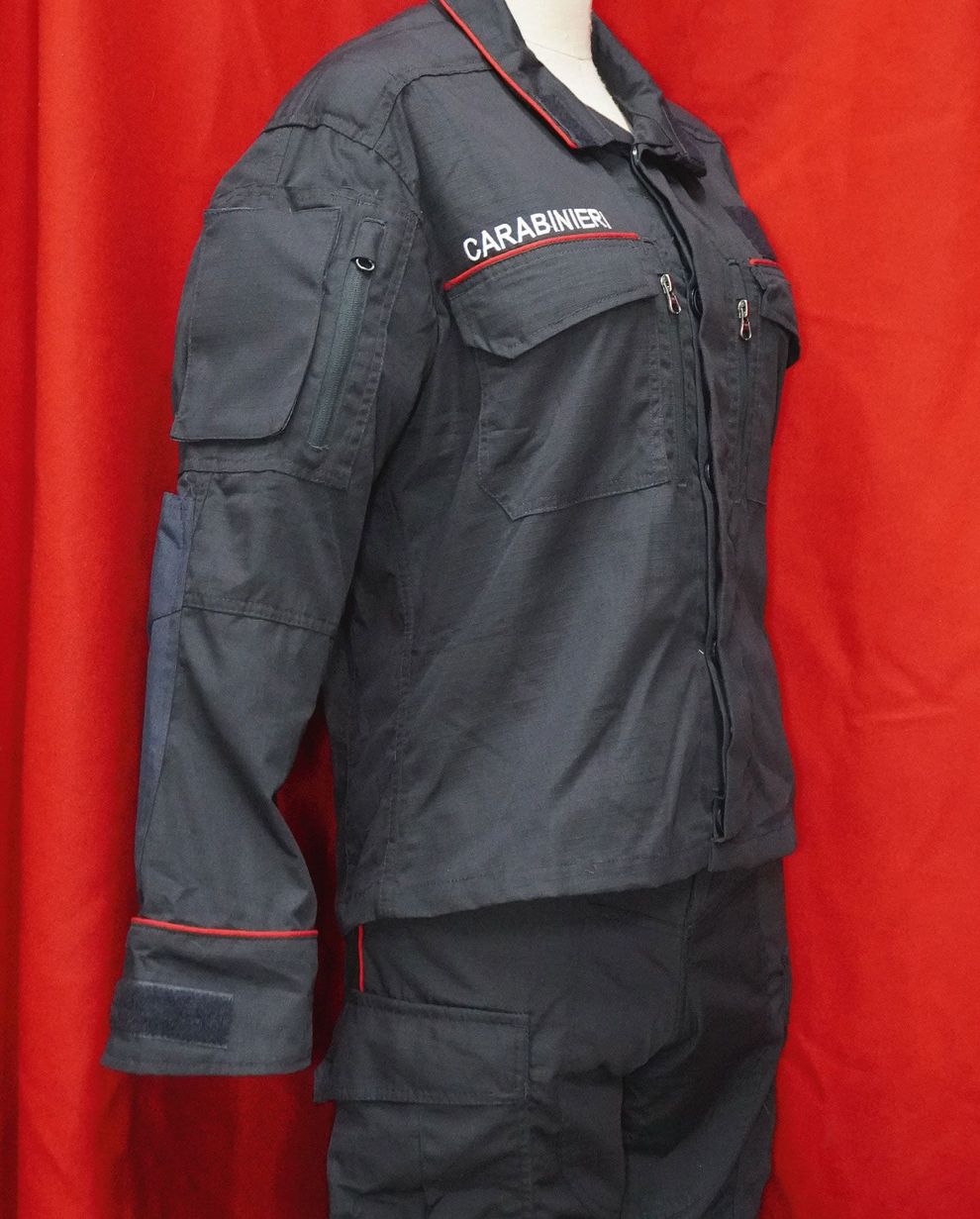 Giacca da lavoro nera Carhartt indossata da un manichino su sfondo rosso.