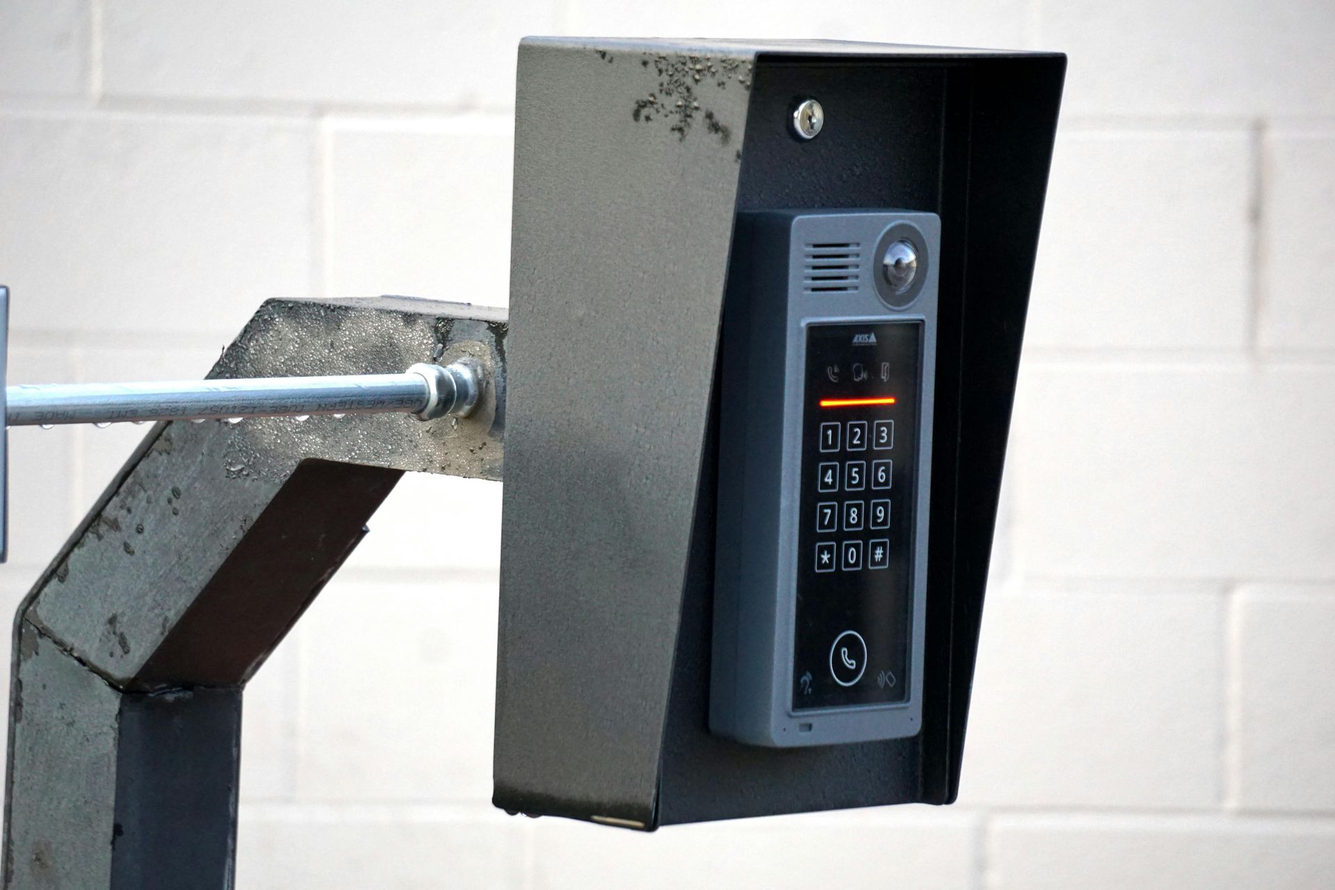 Metal intercom system with keypad and speaker mounted on a wall bracket.