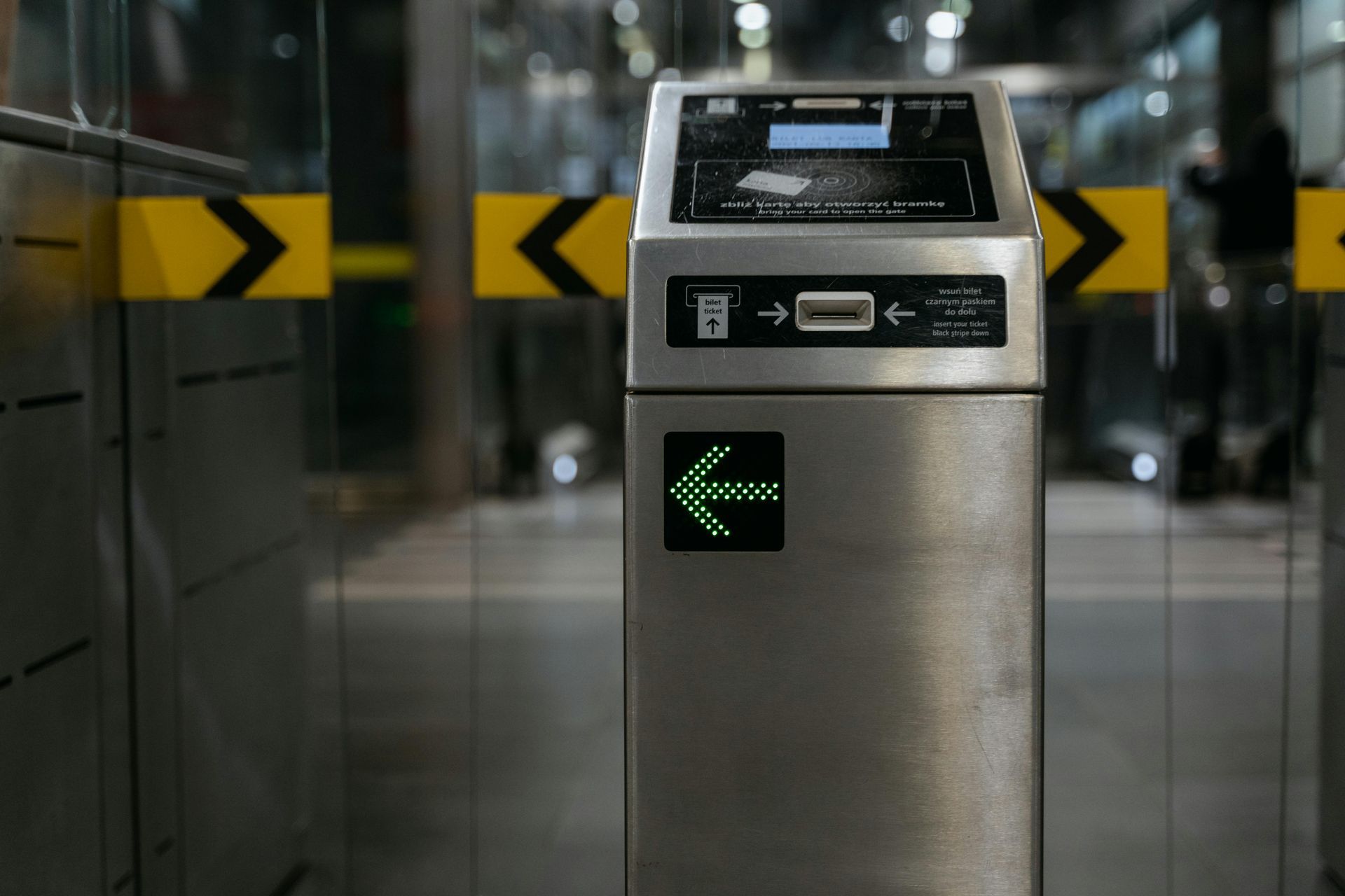A silver subway turnstile with a green arrow lit up, showing the way forward.