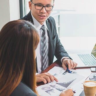 Businessman & Businesswoman Consulting and Discussing Work at Meeting Table — Employee Group Plans in Bozeman, MT Businessman & Businesswoman Consulting and Discussing Work at Meeting Table — Employee Group Plans in Bozeman, MT