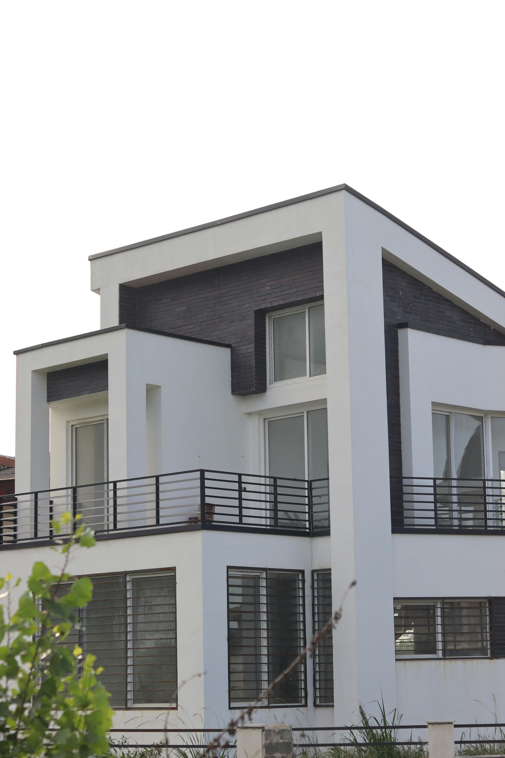 Casa moderna bianca a due piani con balcone e ampie finestre.