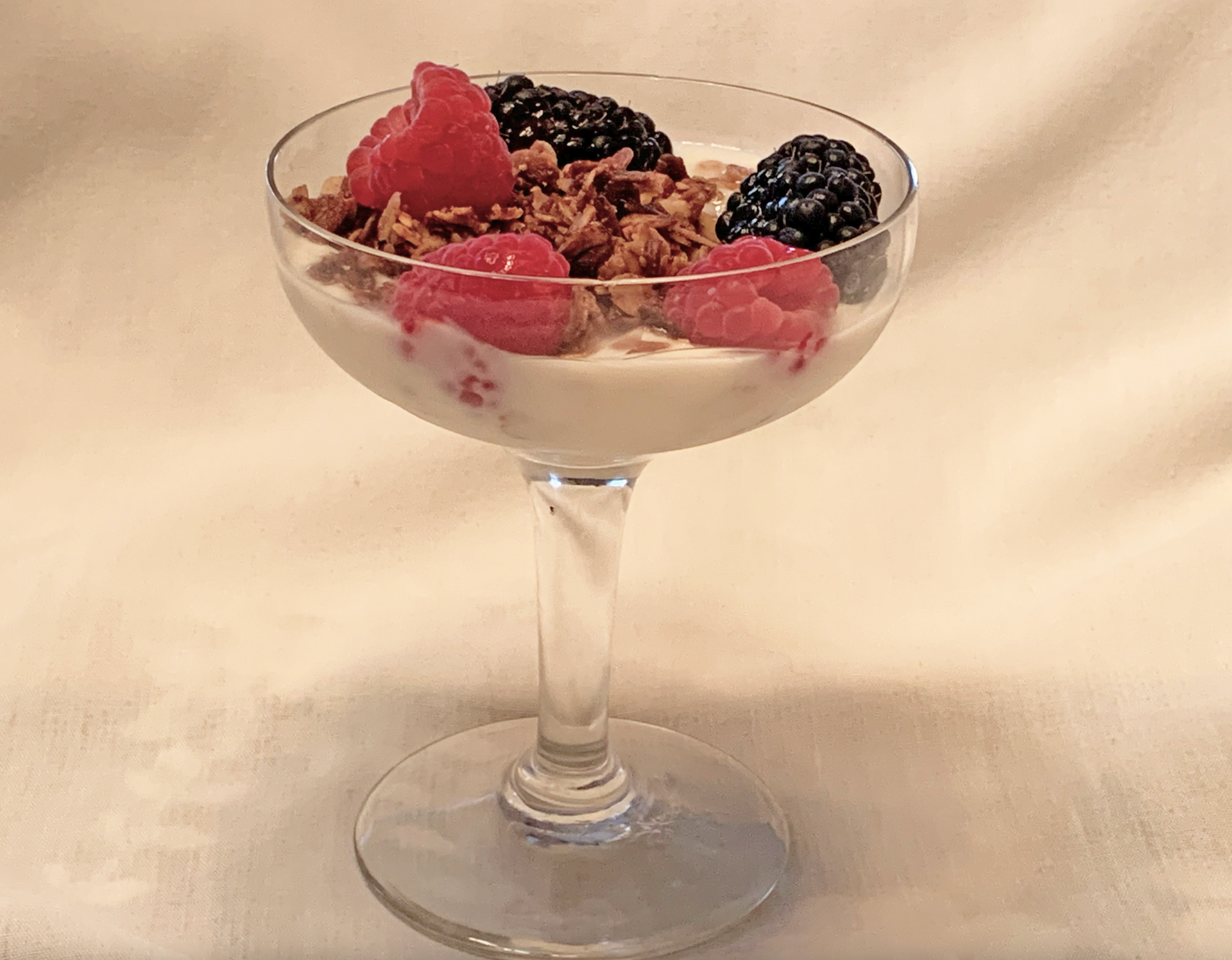 A glass of yogurt with raspberries and blackberries on top