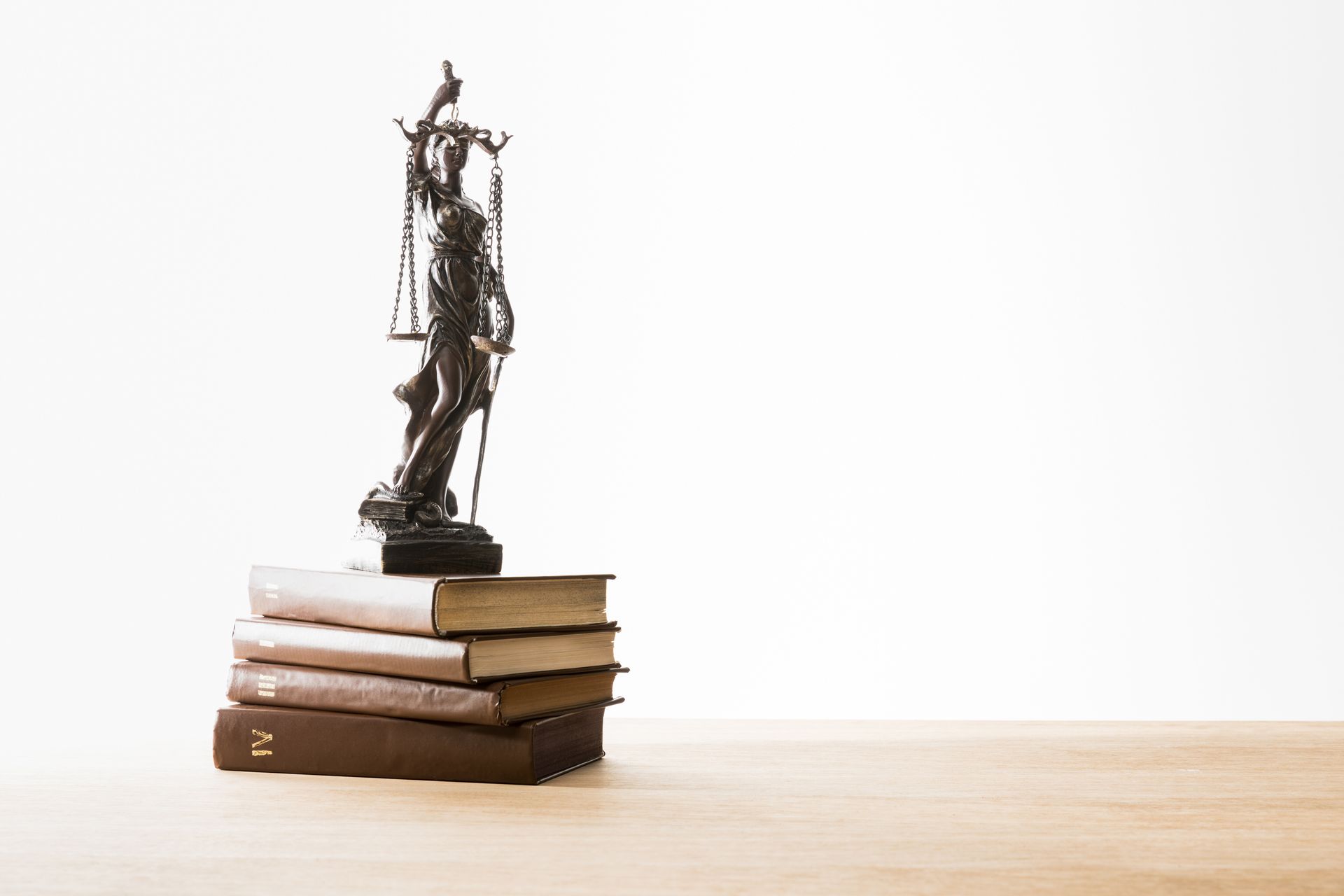 A statue of justice is sitting on top of a stack of books.