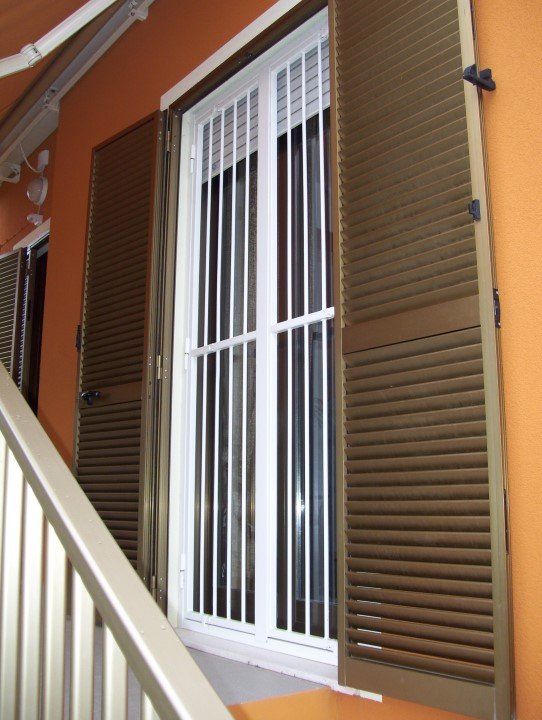 finestra persiane marroni e protezione di ferro bianco
