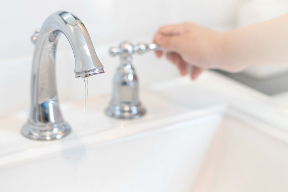 A Hand Turns A Chrome Faucet — DSR Plumbing Pty Ltd in Newcastle, NSW