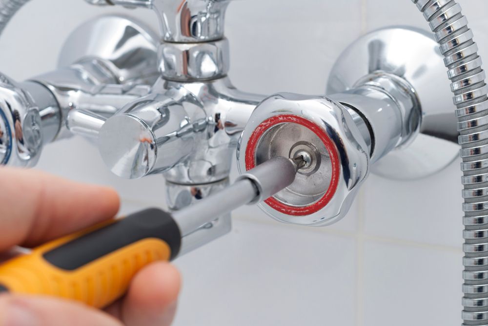 Person Using A Screwdriver To Repair A Chrome Shower Faucet — DSR Plumbing Pty Ltd in Cessnock, NSW