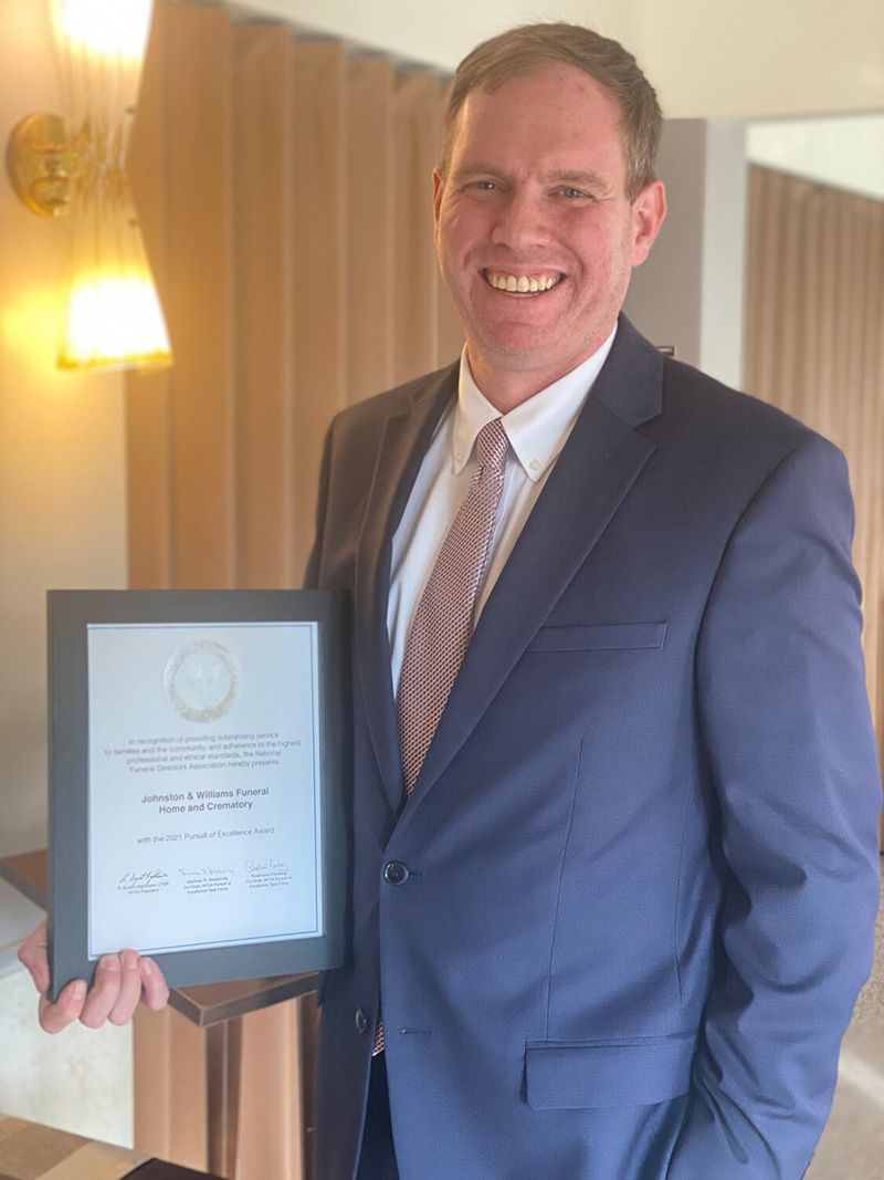 Henry D. Johnston, CFSP, owner of Johnston & Williams Funeral Home and Crematory, displaying the firm's 2021 Pursuit of Excellence certificate from the National Funeral Directors Association