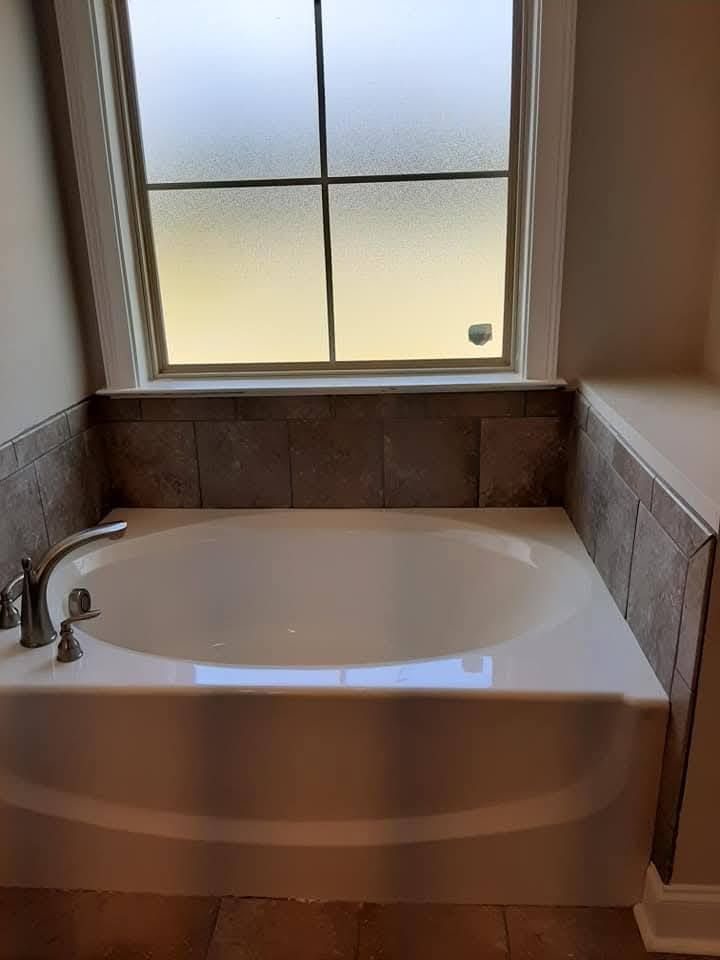 A bathtub in a bathroom next to a window.