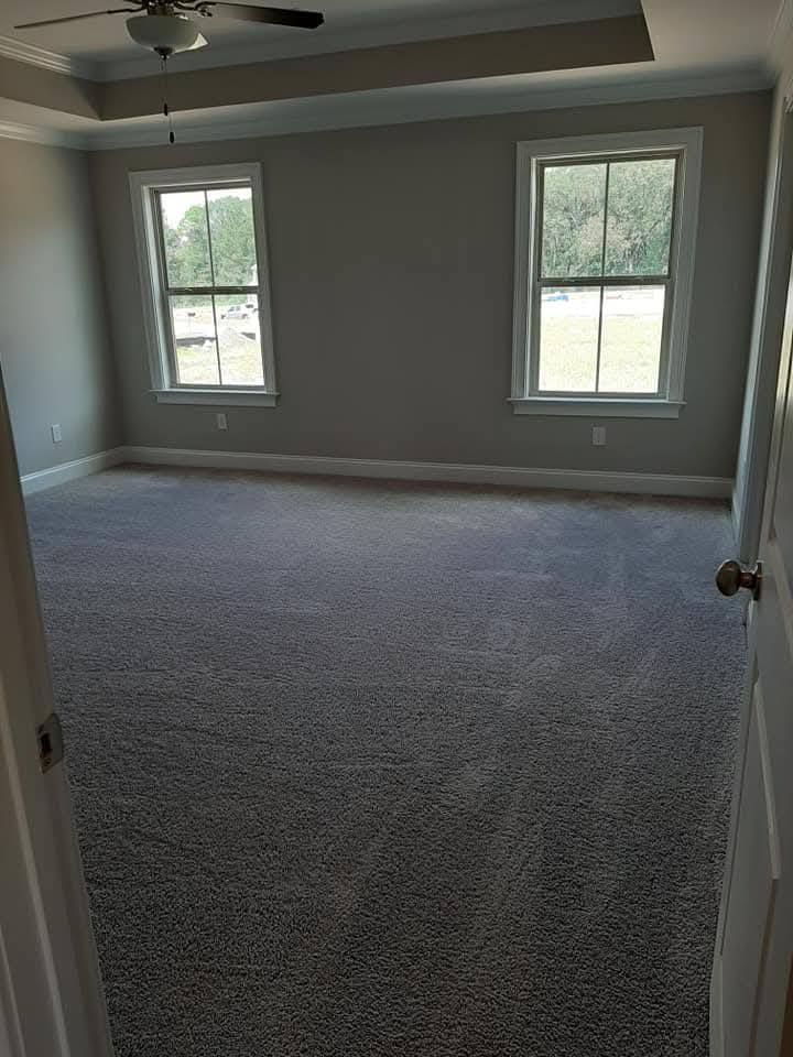An empty bedroom with a ceiling fan and two windows.
