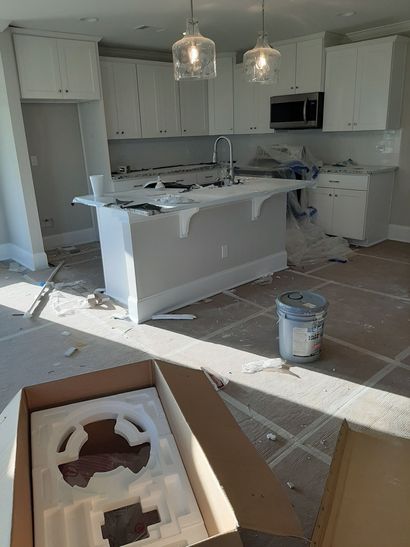 A kitchen under construction with white cabinets and a large island.